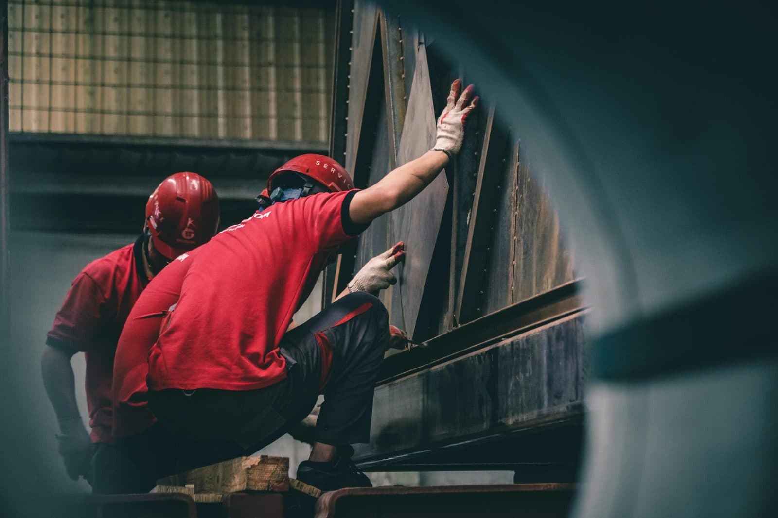 Two workers in red hard hats handling steel on a job site