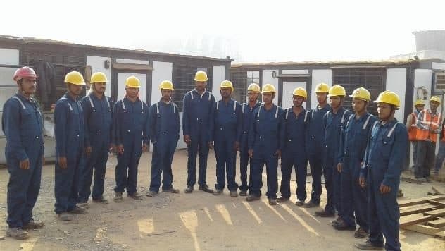 Site crew in hard hats lined up in front of site offices