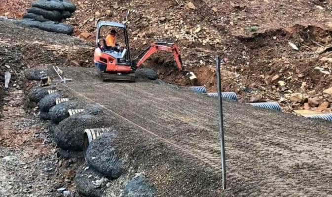 Rock bags staged on a construction site beside an excavator